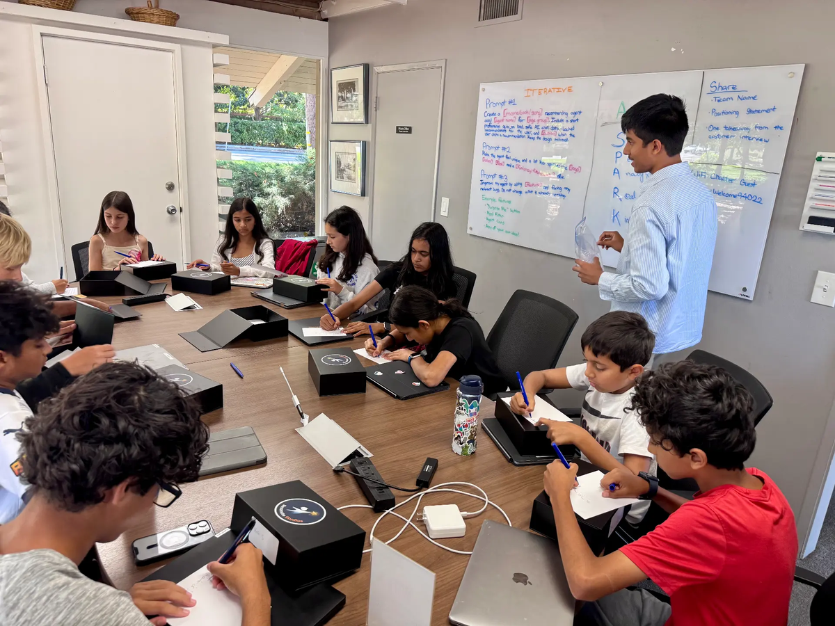 Students collaborating around a laptop in a bright workshop